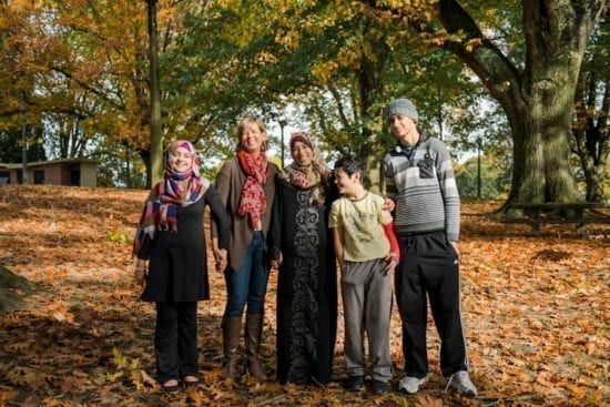 refugee family and volunteer smiling in park