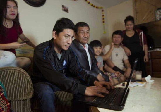 family group gathered around laptop at home